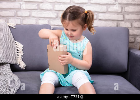 Glückliches Mädchen sitzt auf einem Sofa Eröffnung Paketbox Stockfoto