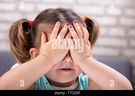 Vorderansicht des netten Mädchens deckt Ihre Augen mit der Hand, bunten Nagellack Stockfoto