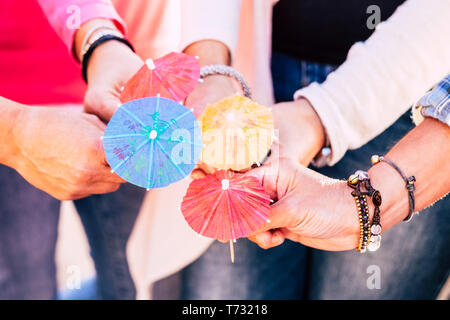 Nahaufnahme mit einer Gruppe von Menschen halten und vier cocktail Schirme zusammen angezeigt - Freundschaft und Zusammenarbeit im Team feiern Konzept Lebensstil Stockfoto