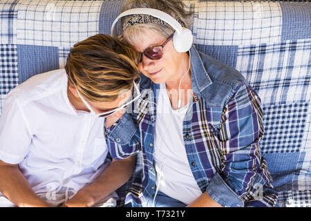 Paar junge und alte Großmutter und Teenager Neffe Familie Zeit zusammen Musik hören mit Kopfhörern und den Tag genießen. Glückliche Familie und Generationen Stockfoto