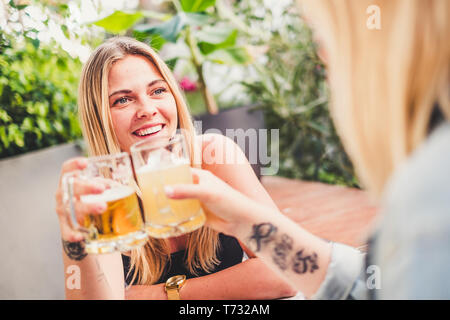 Freundliche Blonde mit Freund an der Bar Bier trinken und feiern in der Freundschaft Toasten die Gläser und gemeinsam Spaß haben - glückliche Menschen Feier Stockfoto