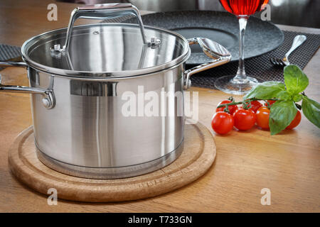 Metall Topf mit Suppe auf einem Holztisch mit zwei Gläsern Rotwein. Stockfoto