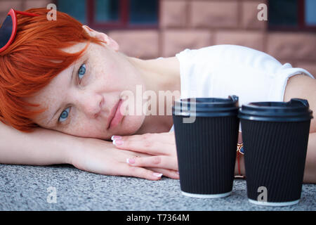 Nahaufnahme einer jungen Frau mit kurzen roten Haaren zu Fuß rund um die Stadt mit ein paar Tassen Kaffee, freier Platz für Text Stockfoto