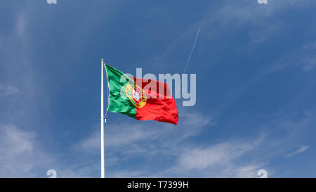 Schöne große Portugiesische Flagge im Wind gegen den blauen Himmel. Portugiesische Flagge schwenkten gegen den blauen Himmel. Flagge Portugals winken, gegen den blauen Sk Stockfoto