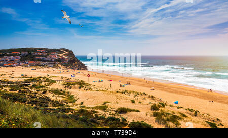 Blick auf den Strand von Monte Clerigo mit fliegenden Möwen auf der westlichen Küste von Portugal, Algarve. Treppen zum Strand Praia Monte Clerigo in der Nähe von Aljezur, Stockfoto