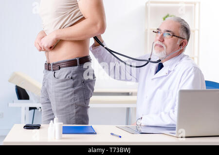 Junge männliche Patienten besuchen alte Arzt Stockfoto