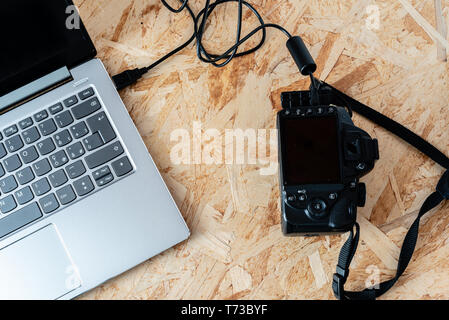 Notebooks auf eine digitale SLR-Kamera mit USB-Kabel angeschlossen, thetering Modus, auf einem Desktop Stockfoto