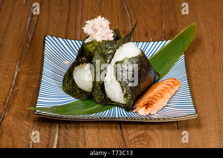 Onigiri gebratener Thunfisch und Lachs, in Seetang eingewickelt, darl Holz Tisch Hintergrund Stockfoto