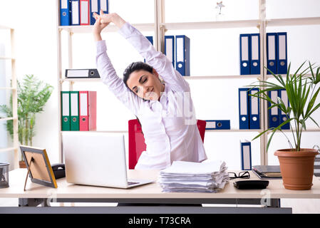 Junge weibliche Mitarbeiter Übungen im Büro Stockfoto