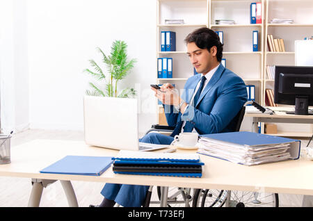 Männliche Angestellte im Rollstuhl im Büro arbeiten Stockfoto