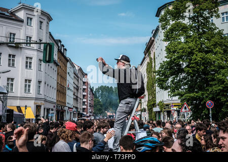 Berlin, Deutschland - 01.Mai 2019: Person auf der Leiter der Aufnahme von überfüllten Street Festival am Tag der Arbeit in Berlin, Kreuzebreg Stockfoto