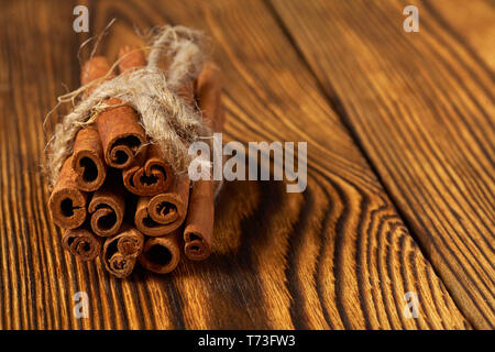 Bündel von Zimt mit einem Seil auf einer hölzernen Hintergrund gebunden. Stockfoto