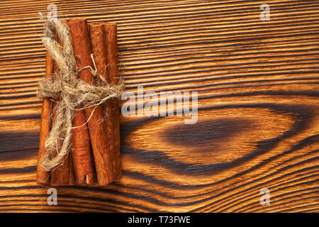 Bündel von Zimt mit einem Seil auf einer hölzernen Hintergrund gebunden. Stockfoto