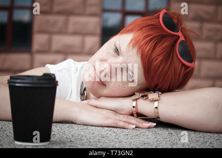 Nahaufnahme einer jungen Frau mit kurzen roten Haaren zu Fuß rund um die Stadt mit ein paar Tassen Kaffee, freier Platz für Text Stockfoto