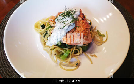 Frisch gebackenen Lachs auf Nudeln mit Spinat und Sellerie. Fischgericht serviert auf einem tiefen Teller. Das gesunde Essen. Stockfoto