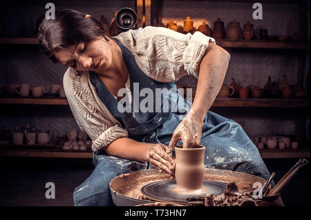 Charmante handicraftsman zeigt, wie mit Ton und Tonwaren Rad zu arbeiten. Die keramischen Gerichte. Stockfoto
