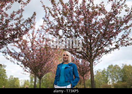 Junge blonde Mutter Frau genießen Freizeit - in blauer Jacke und weißen Hosen gekleidet Stockfoto