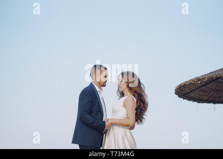 Schönen jungen langhaarigen Braut im weißen Kleid mit ihr junger Ehemann am Strand Stockfoto
