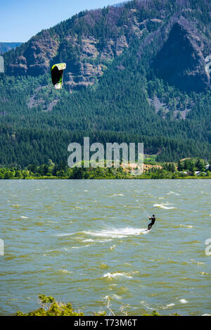 Ein Kitesurfer, der den starken Frühling genießt, schlängelt sich durch die Columbia River Gorge in Stevenson, Washington. Die Oregon-Seite der Columbia Gorge kann ... Stockfoto