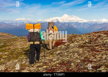 Der Mann und die Frau mit dem Rucksack auf den Herbst farbige Tundra Richtung Denali auf der Kesugi Ridge Trail, Denali State Park, South-central Alaska Stockfoto