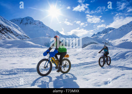 Zwei Frauen fat Bike vor skookum Gletscher, Chugach National Forest, Alaska an einem sonnigen Wintertag, South-central Alaska Stockfoto