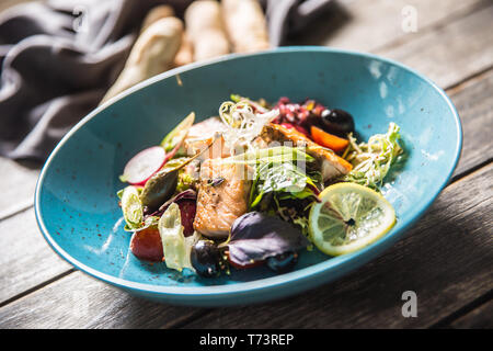 Frisches Gemüse Salat mit gebratenem Lachs Olivenöl und Baguette. Stockfoto