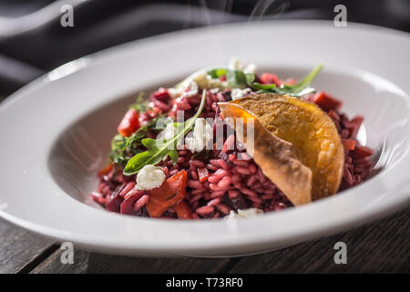 Rote Bete Risotto mit Feta Käse Kartoffelchips Rucola und Olivenöl. Stockfoto