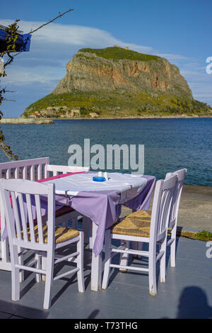 Traditionelle griechische Taverne mit Holztischen am Sandstrand in der Nähe von Wasser für Touristen in Monemvasia, Peleponnes, Griechenland, Ferienhäuser Saison ist Star Stockfoto