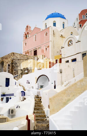 Blick auf eine Gasse, die zu weißen und pastellfarbenen Häusern in Oia (Ia), Santorini, Kykladen, Griechenland führt Stockfoto