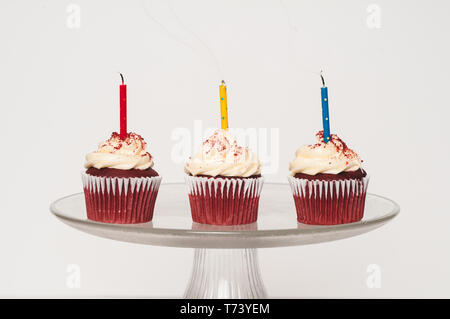 Drei Cupcakes mit Zuckerguss auf einem Kuchen stand Stockfoto