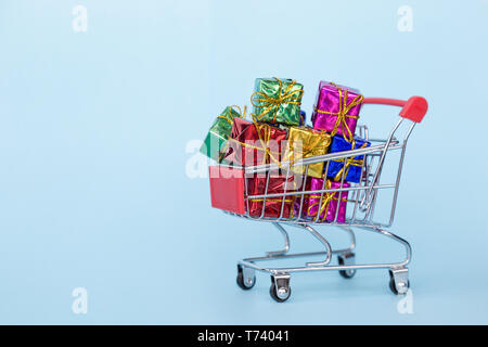 Weihnachten Geschenke in einem Supermarkt Trolley auf blauem Hintergrund mit Freiraum für Text Stockfoto