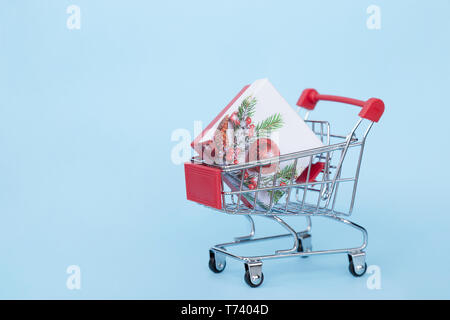 Weihnachten Geschenke in einem Supermarkt Trolley auf blauem Hintergrund mit Freiraum für Text Stockfoto