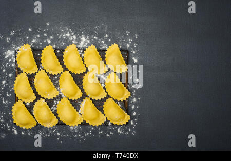 Leckere rohe Ravioli mit Mehl auf dunklem Hintergrund. Prozess des italienischen Ravioli. Horizontal mit kopieren. Essen Konzept. Stockfoto