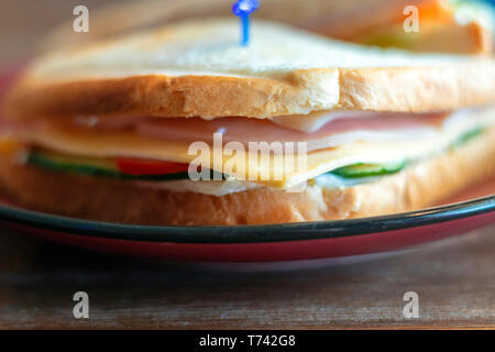 Nahaufnahme einer Club Sandwich. Sandwich mit Treffen, Prosciutto, Salami, Salat, Gemüse, Salat, Tomaten, Zwiebeln und Senf auf einer frischen in Scheiben geschnittenen Roggen Stockfoto