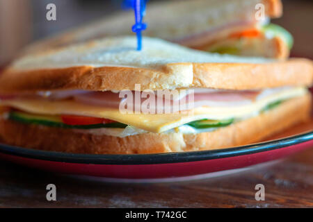 Nahaufnahme einer Club Sandwich. Sandwich mit Treffen, Prosciutto, Salami, Salat, Gemüse, Salat, Tomaten, Zwiebeln und Senf auf einer frischen in Scheiben geschnittenen Roggen Stockfoto
