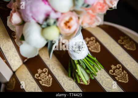 Schönen brautstrauß von Pfingstrosen und Rosa Rosen, mit einer Brosche auf einem Stuhl eingerichtet Stockfoto