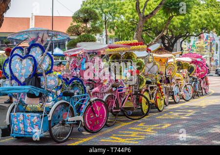 Malakka, Malaysia - April 21,2019: Die farbenfroh gestalteten Rikschas sind Parkplätze in Dutch Square Malacca warten auf Kunden. Malacca gelistet Stockfoto