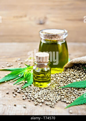 Hanf Öl in zwei Gläser mit Getreide im Sack, Blätter und Stängel von Cannabis auf dem Hintergrund der Holzbretter Stockfoto