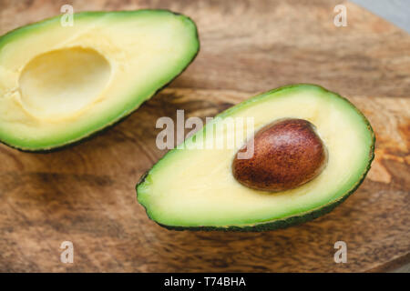 Die beiden Hälften des frischen Rip-Avocado auf einem Holzbrett. Close Up, selektive konzentrieren. Stockfoto