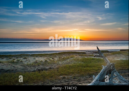 Die untergehende Sonne über Alaskas Mount Susitna, lokal bekannt als "The Sleeping Lady", mit dem Cook Inlet im Vordergrund, wie vom Point Worzeno aus gesehen... Stockfoto