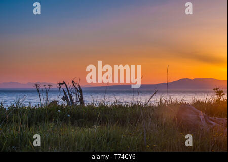 Die untergehende Sonne über Alaskas Mount Susitna, lokal bekannt als "The Sleeping Lady", mit dem Cook Inlet im Vordergrund, wie vom Point Worzeno aus gesehen... Stockfoto