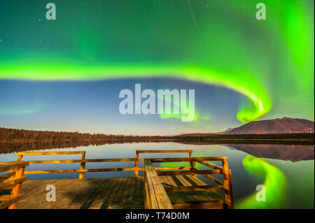 Die Nordlichter gesehen reflektiert Strand See auf eine klare, Herbst Nacht mit einer Holzterrasse im Vordergrund. Stockfoto