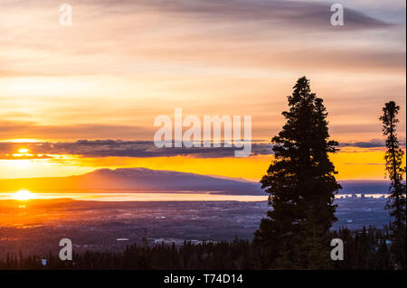 Die untergehende Sonne über Alaskas Mount Susitna, lokal bekannt als "The Sleeping Lady", mit dem Cook Inlet und der Stadt Anchorage im Vordergrund ... Stockfoto