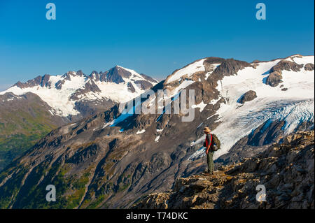 Der Kenai Fjords National Park, ein Mann, der in der Nähe des Harding Icefield Trail mit den Kenai Mountains und einem namenlosen hängenden Gletscher... Stockfoto