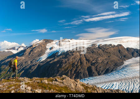 Der Kenai Fjords National Park, ein Mann, der in der Nähe des Harding Icefield Trail mit den Kenai Mountains und einem namenlosen hängenden Gletscher... Stockfoto