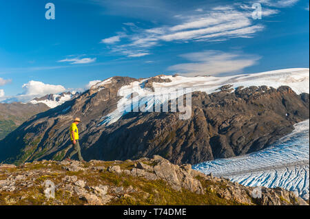 Der Kenai Fjords National Park, ein Mann, der in der Nähe des Harding Icefield Trail mit den Kenai Mountains und einem namenlosen hängenden Gletscher... Stockfoto