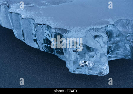 Close-up ein Stück Eis in den schwarzen Sand an der Südküste Islands sitzen ; Island Stockfoto