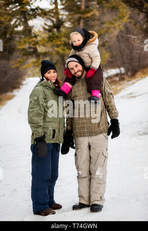 Eine junge Familie Wandern Natur mit ihrer kleinen Tochter während eines Winters Familienausflug: Fairmont, British Columbia, Kanada Stockfoto