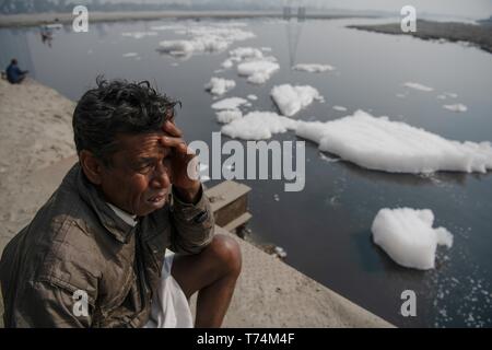 Neu-delhi, Delhi, Indien. 11 Jan, 2019. Ein einheimischer Fischer gesehen Vorbereiten der Fische in den Yamuna-fluss durch Aufschäumen von der Entlassung von unbehandelten industriellen und häuslichen Abfällen bedeckt, in der Nähe von Klaindi Kunj. Yamuna-fluss, oft als Delhis Lifeline, wurde als "ökologisch tot'' für seine scheinbare Unfähigkeit gekennzeichnet sein ursprüngliches limpidness wiederzugewinnen. Yamuna ist überfüllt mit Schaum als Ergebnis der unbehandelten industriellen und häuslichen Abfälle in den Fluss. Der drastische Rückgang der Sauerstoffgehalt ist verantwortlich für die Tötung der verschiedenen Arten und Beeinträchtigung der Ökologie. Dies ist sogar ein Econ Stockfoto