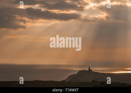 Eastbourne, East Sussex, Großbritannien. Mai 2019. Strahlen durch die zunehmende Wolkendecke bei Sonnenuntergang machen eine erstaunliche Szene. Bild aus dem Bereich "Beachy Head" mit Blick nach Westen und dem Leuchtturm "Belle Tout" Direkt im Zentrum. Stockfoto